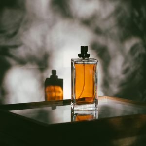 A stylish perfume bottle casting shadows on a reflective surface, creating a moody ambiance.