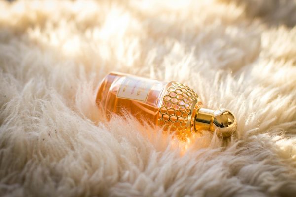 Elegant perfume bottle with gold details resting on fluffy white fur, capturing luxury and glamour.